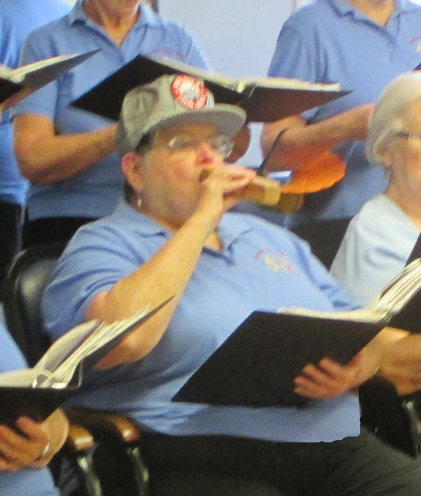Photo shows one of the singers wearing a railroad hat and blowing a train whistle.