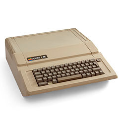 Photo shows a tan-colored device about a foot square and 2 inches thick, with a regular (querty) keyboard on one end.
