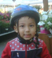 Photo shows Navin on a porch, smiling at the camera and wearing a bicycle helmet.