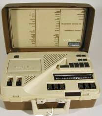 Photo shows VersaBraille I.  Its hinged cover is open, showing an 6 braille keys and a space bar, a braille display of about 20 cells, several other buttons, and an indentation that looks like it might hold a cassette tape.