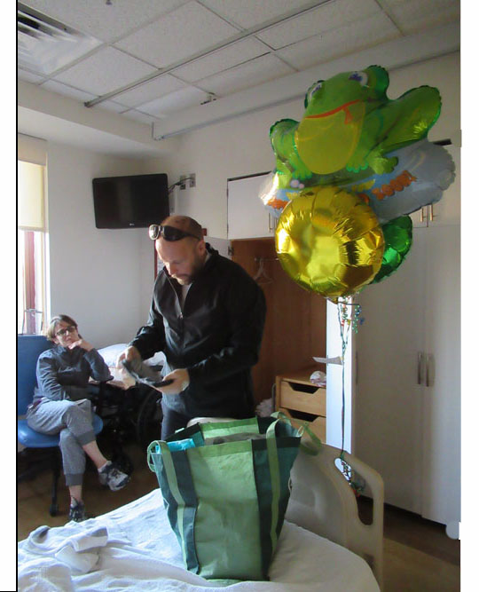 Two pictures show Paul standing at the foot of his bed with a cloth shopping bag, putting clothes into it.  Jomania is sitting on a couch behind him and watching, grinning in one of the pictures.  The large baloons are tied to the end of the bed.