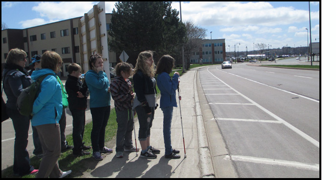 Both photos show the students lined up to face the street and listen to the traffic, with instructors standing beside the line.