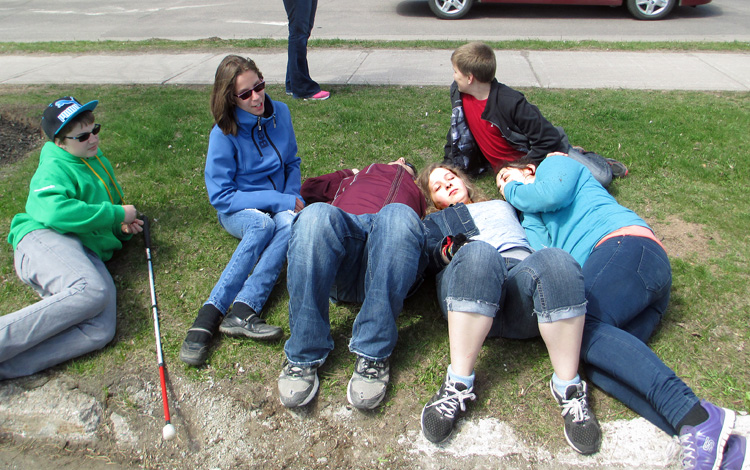 Both photos show the students sitting or lying on the grass and talking quietly.