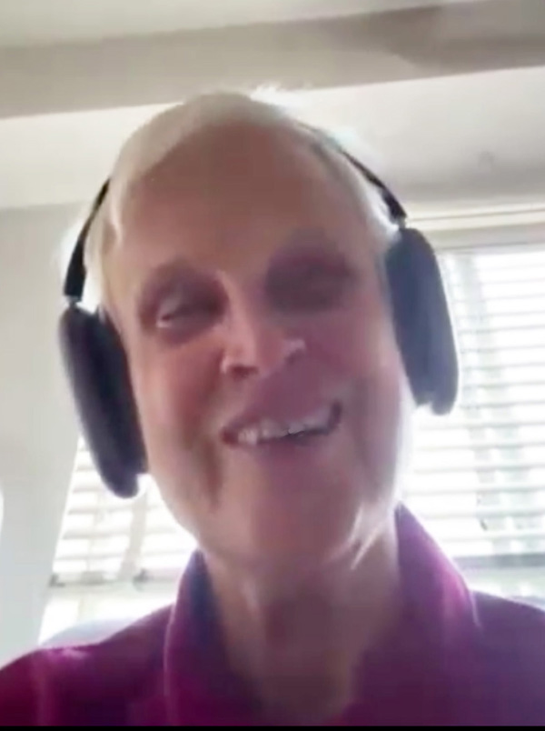 Linda Kipps is a white woman with short white hair, wearing headphones and smiling broadly.