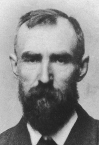 photo of Thomas Lucas (from the chest up) shows him as a middle-aged man with a full beard, wearing a coat and tie