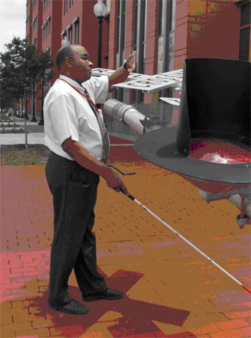 photo shows the same man approaching the same rod, but with his right hand holding the cane, his left arm is positioned horizontally with the elbow bent so that his forearm and hand are diagonally in front of his face and contacting the object (we now see that the 'rod' is actually the pole of a railroad sign that for some unknown reason is protruding diagonally from the ground -- there is construction nearby, and this railroad sign has been left here).