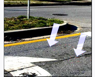 Photo shows a street with two grey parallel lines in the middle of the left-turning lane -- the lines are parallel and about 3 feet apart