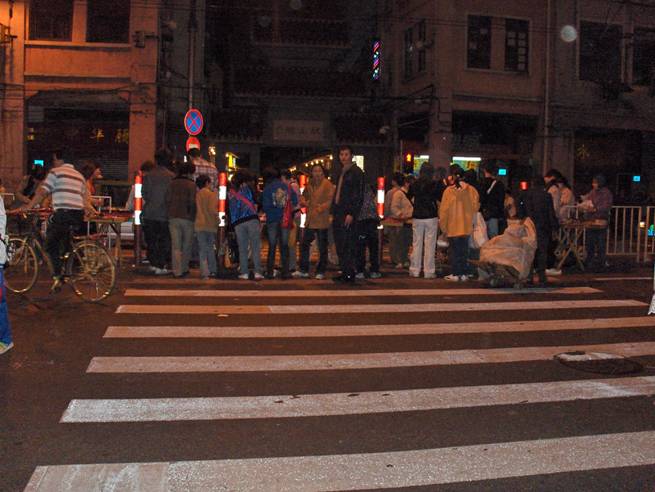 photo shows a crosswalk about 3 lanes to the middle.  The middle is completely blocked with people standing around or looking at several tables.