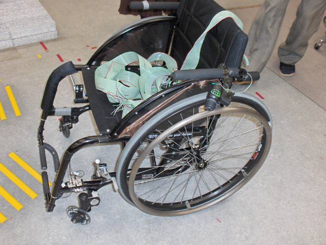An wheelchair has ribbons of wire sitting on the seat and going to the back.