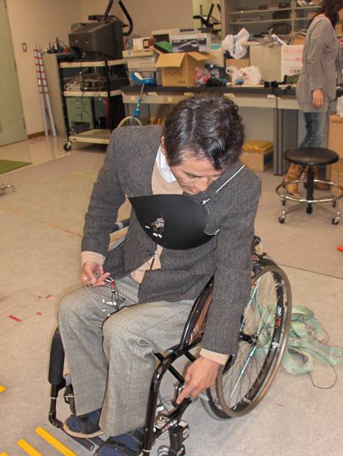 Professor Nakamura is sitting in the chair, wearing a square of materia on his chest that is attached with wires