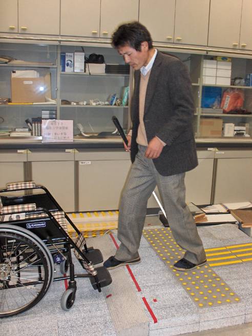 Photo shows Professor Nakamura's foot going over the slope.  On the other side of the slope is the wheelchair, facing to go up the slope.