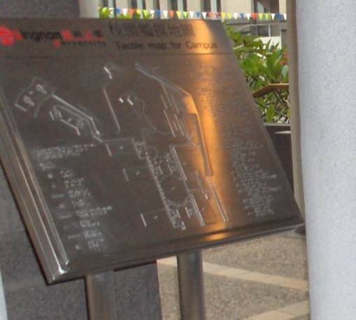a close-up of the metal tactile map shows braille legend and symbols, and raised shapes representing the buildings and walkways.