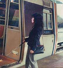 A young woman enters a metro subway car, with her white cane on the floor inside the car.