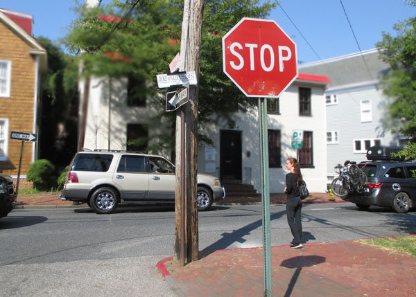 Photo shows a man starting to walk across a residential street from a corner.  We can see the stop sign for the street beside him.