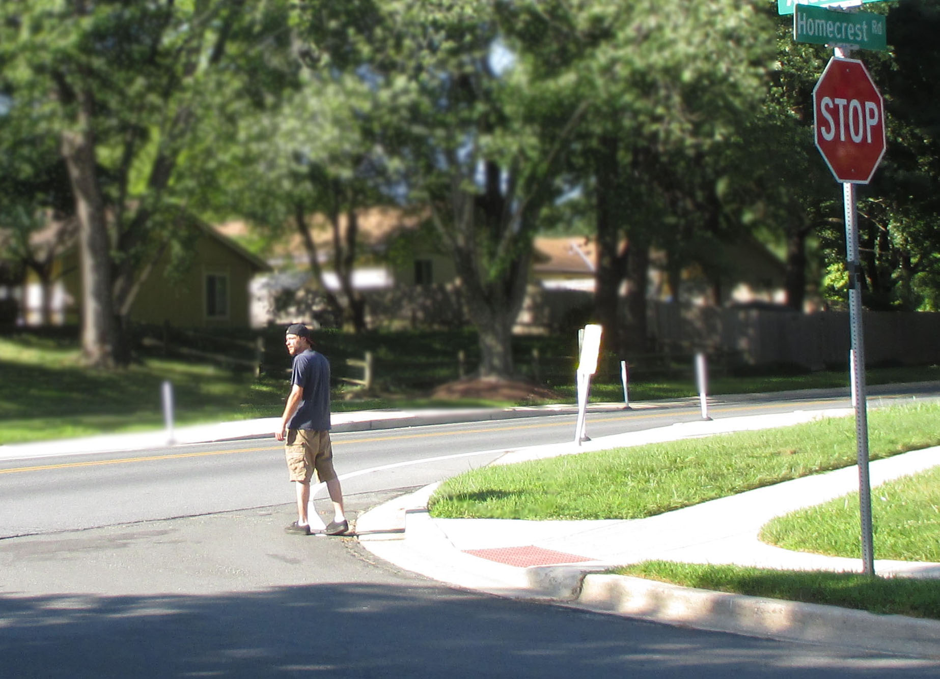 Photo shows a man starting to walk across a residential street from a corner.  We can see the stop sign for the street beside him.