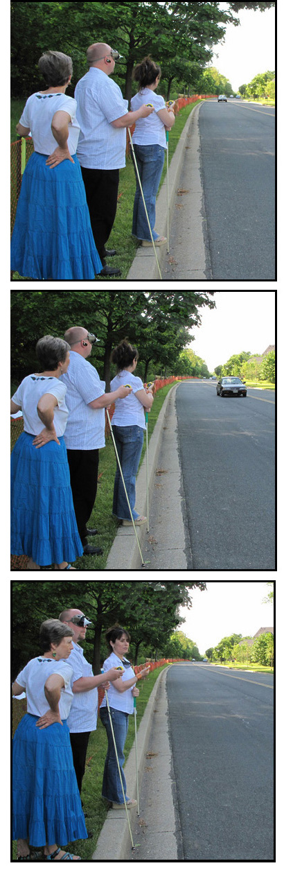 3 photos show a man and a woman standing at the curb of a straight street, holding stopwatches -- the man is wearing a vision simulator for restricted visual fields.  Dona stands to their right.  They are both watching a car approach from the left and pass them.