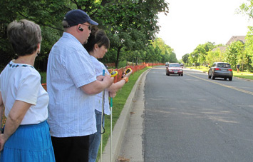 two photos show Paul and Jomania standing at the straight street with stopwatches as cars approach from the right and left.