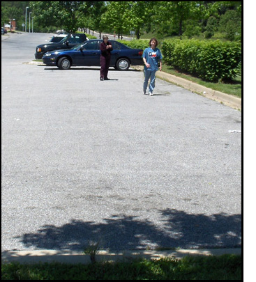 Photo shows Stephan in the parking lot starting to walk from the lane marker toward the curb, while Dona holds a stopwatch.