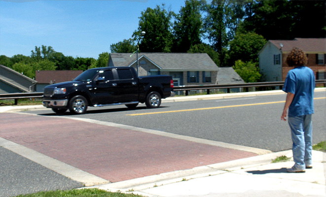 Photo shows the dark truck at the crosswalk.